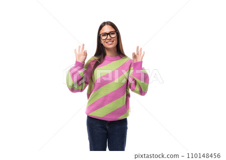 portrait of a smart young brunette woman in a casual stylish pink-green sweater on a white 110148456