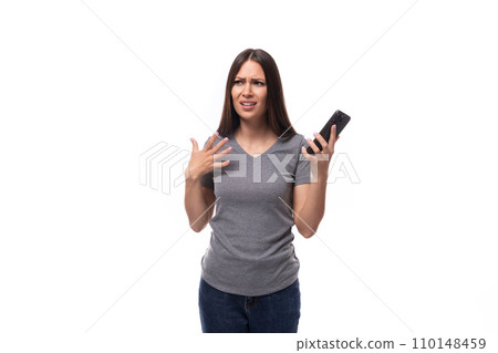 young slender brunette promoter woman dressed in a gray t-shirt uses a smartphone on a white 110148459