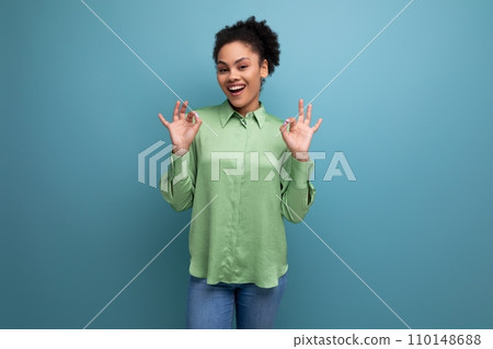 young positive female model with curly black hair dressed in a green blouse and jeans is smiling young positive female model with curly black hair dressed in a green blouse and jeans is smiling 110148688