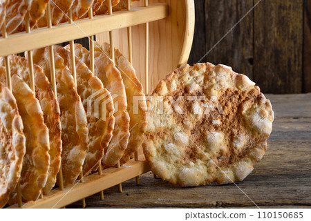Typical South Tyrolean local crunchy flat bread, so called schuettelbrot, with wooden shelf 110150685