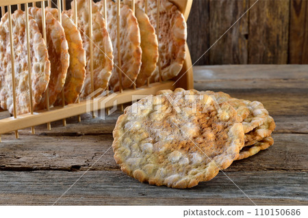 Typical South Tyrolean local crunchy flat bread, so called schuettelbrot, with wooden shelf 110150686