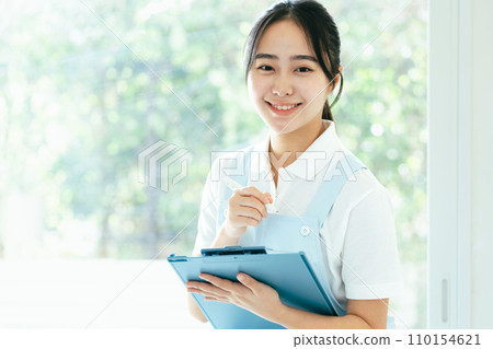 Young female caregiver standing by the window Young female caregiver standing by the window 110154621