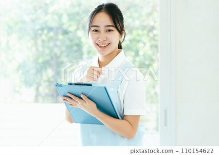 Young female caregiver standing by the window Young female caregiver standing by the window 110154622