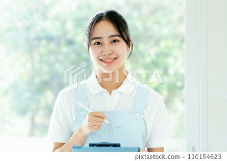 Young female caregiver standing by the window Young female caregiver standing by the window 110154623