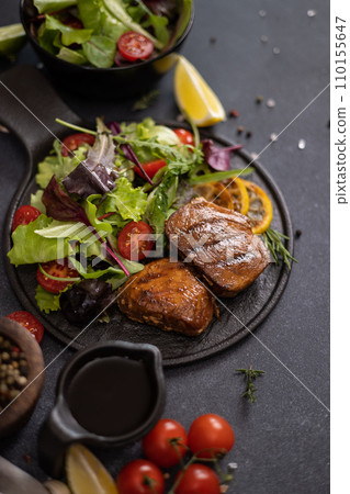 pieces of Organic grilled Tuna Steak on black ceramic serving dish with salad on a table pieces of Organic grilled Tuna Steak on black ceramic serving dish with salad on a table 110155647