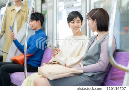 A young woman and her friends ride the train while looking at their smartphones. Photography provided by Keio Electric Railway Co., Ltd. A young woman and her friends ride the train while looking at their smartphones. Photography provided by Keio Electric Railway Co., Ltd. 110156707