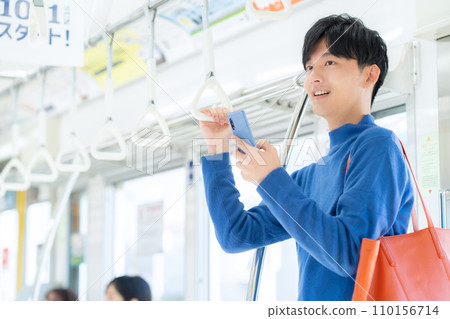 Young man looking at smartphone on train 110156714