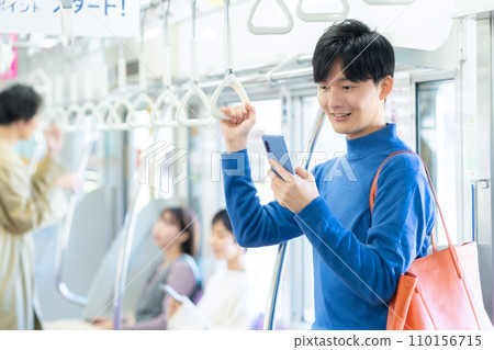 Young man looking at smartphone on train 110156715