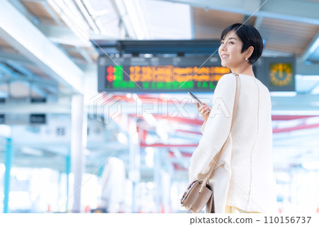 Young woman walking through the station while looking at her smartphone. Photography provided by Keio Electric Railway Co., Ltd. 110156737
