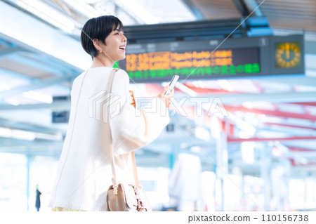 Young woman walking through the station while looking at her smartphone. Photography provided by Keio Electric Railway Co., Ltd. 110156738
