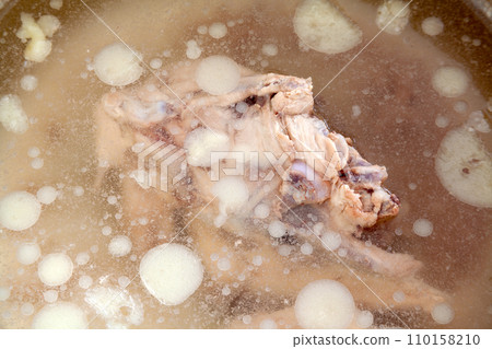 A pot with a lot of chicken fat floating in the stock made from chicken bones. 110158210