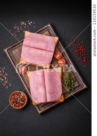 Delicious sandwich with toast bread, ham, tomatoes, salt and spices 110159530