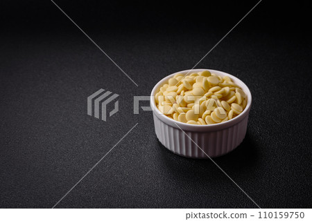 Round granules of sweet confectionery chocolate as an ingredient for preparing delicious desserts Round granules of sweet confectionery chocolate as an ingredient for preparing delicious desserts 110159750