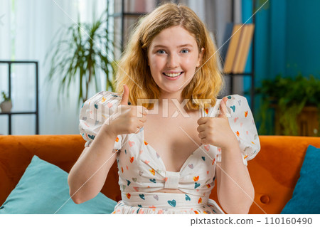 Happy young woman looking approvingly at camera showing thumbs up, like positive sign, good news 110160490