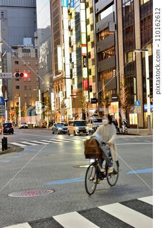 A woman crosses Ginza Chuo-dori on a bicycle A woman crosses Ginza Chuo-dori on a bicycle 110162612