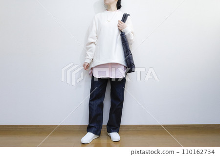 A woman wears a spring-colored shirt and a white fleece pullover, a men's casual outfit. 110162734