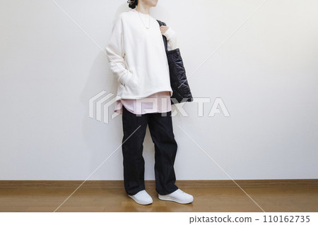 A woman wears a spring-colored shirt and a white fleece pullover, a men's casual outfit. 110162735