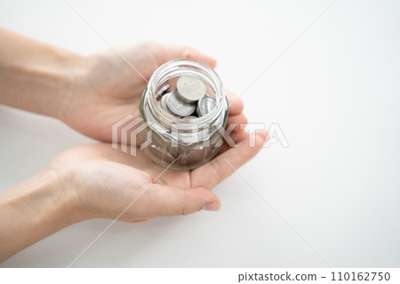 一個裝滿儲蓄和硬幣的透明罐子，適合您的手 110162750