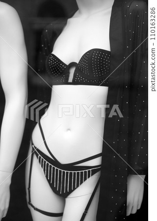 Closeup of black bras and strass with a black transparent shirt on mannequin in a fashion store showroom Closeup of black bras and strass with a black transparent shirt on mannequin in a fashion store showroom 110163286