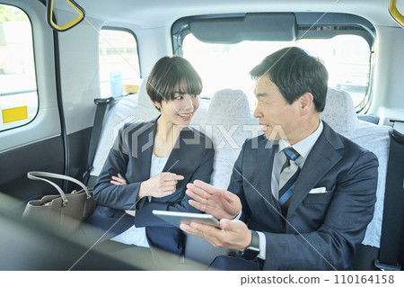 A male office worker in his 50s and a female office worker in her 30s having a meeting in a taxi 110164158