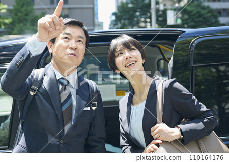 A male office worker in his 50s and a female office worker in her 30s using a taxi A male office worker in his 50s and a female office worker in her 30s using a taxi 110164176