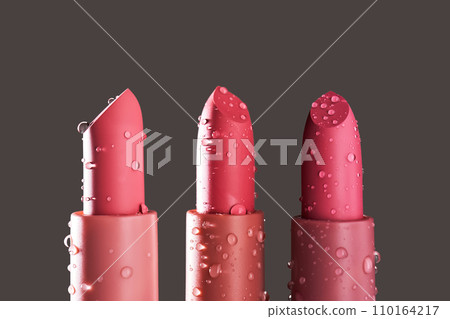 Red lipsticks with water drops on a dark background. Red lipsticks with water drops on a dark background. 110164217