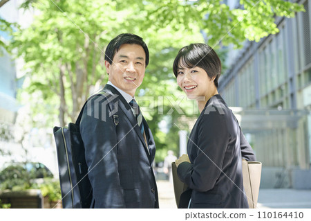 A male office worker in his 50s and a female office worker in her 30s walking in a business district A male office worker in his 50s and a female office worker in her 30s walking in a business district 110164410