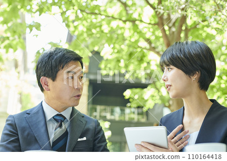 A male office worker in his 50s and a female office worker in her 30s having a meeting on the terrace A male office worker in his 50s and a female office worker in her 30s having a meeting on the terrace 110164418