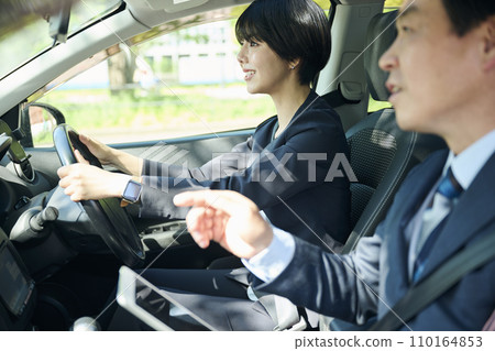 A male office worker in his 50s and a female office worker in her 30s talking in the car A male office worker in his 50s and a female office worker in her 30s talking in the car 110164853