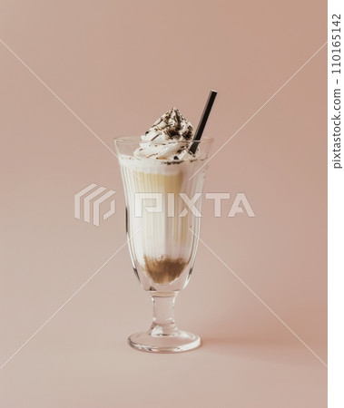 AI-generated content. Chocolate milkshake in elegant glass decorated with whipped cream, chocolate shavings and cocktail straw. Isolated on milk coffee background. 110165142