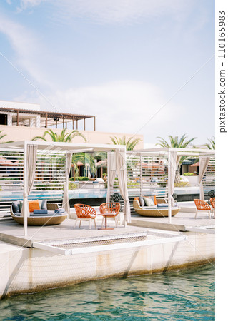 Wooden gazebos with armchairs and sofas on the pier by the sea. One and Only, Portonovi, Montenegro Wooden gazebos with armchairs and sofas on the pier by the sea. One and Only, Portonovi, Montenegro 110165983