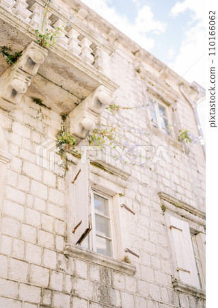 Open white wooden shutters on the windows of an ancient stone house Open white wooden shutters on the windows of an ancient stone house 110166062