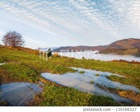 Hazy and overcast autumn Carpathian Mountains and dirty countryside path, Ukraine. Hazy and overcast autumn Carpathian Mountains and dirty countryside path, Ukraine. 110166327