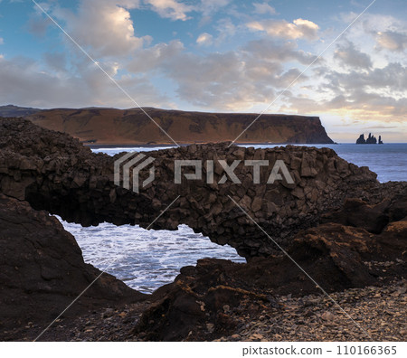 Picturesque autumn evening view to Reynisfjara ocean  black volcanic sand beach and rock formations from Dyrholaey Cape, Vik, South Iceland. Mount Reynisfjall on the background. 110166365