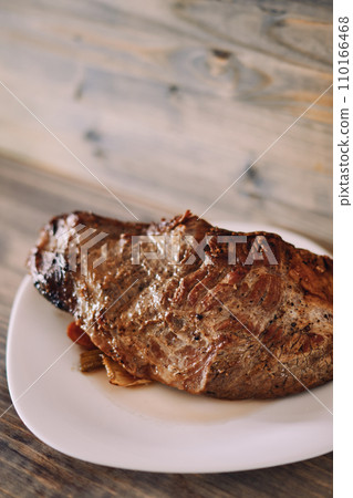 Baked piece of tenderloin with vegetables lies on a plate on the table 110166468
