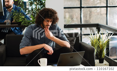 Analyst looks for inspiration to create software program, AI developer thinking about investment in coworking space. Creative businessman reviewing analytics data to work on profit. 110167102