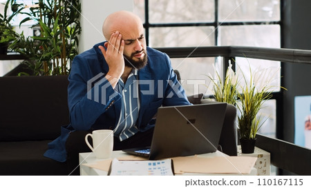 Analyst dealing with headache at work, trying on examine annual data strategy but feeling unwell. Sick employee working on development project with migraine, being overworked. Handheld shot. 110167115