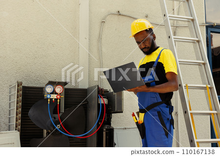 African american specialist hired after home owner complaints about significant increase in energy bills. Knowleadgeable engineer using ac gauges vacuum pump to detect refrigerant leaks 110167138