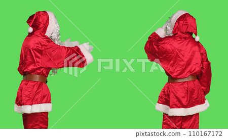 Santa cosplay giving air kisses on camera, doing sweet gesture over greenscreen background in studio. Young adult in red costume acting flirty and romantic with someone, christmas eve. 110167172