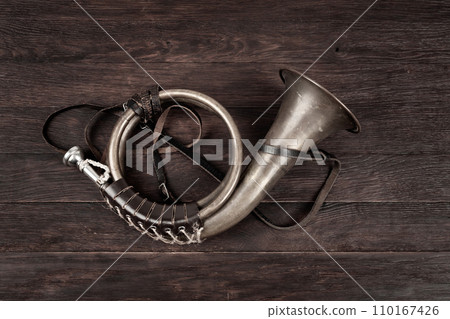 Hunting horn on rustic wood plank. 110167426