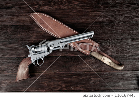 Old west weapon. Colt Revolver and knife with holster on deck. Old west weapon. Colt Revolver and knife with holster on deck. 110167443