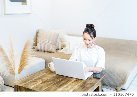 A woman drinking tea while looking at a computer A woman drinking tea while looking at a computer 110167470