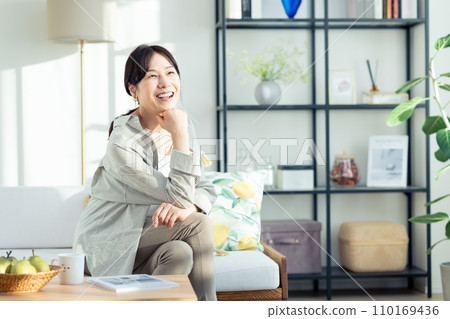 A middle-aged woman relaxing in the living room A middle-aged woman relaxing in the living room 110169436