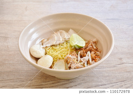 dry spicy tom yum Chinese yellow egg noodles with slice pork and ball couple fish line topping lemon on bowl dry spicy tom yum Chinese yellow egg noodles with slice pork and ball couple fish line topping lemon on bowl 110172978