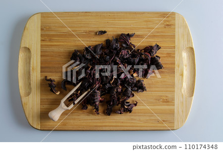 Tea made from dried pomegranate flowers. Increases immunity. Wooden spatula with tea and a handful of tea mixture on a wooden board 110174348