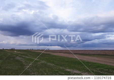 A vast field under a cloudy sky at dusk. 110174728