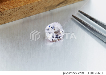 macro mineral faceted stone Morganite with tweezers on a gray background macro mineral faceted stone Morganite with tweezers on a gray background 110176611