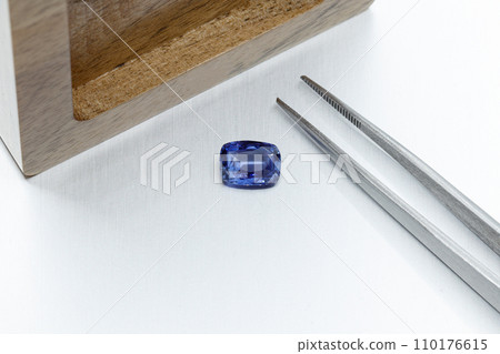 macro mineral faceted stone sapphire with tweezers on a gray background macro mineral faceted stone sapphire with tweezers on a gray background 110176615
