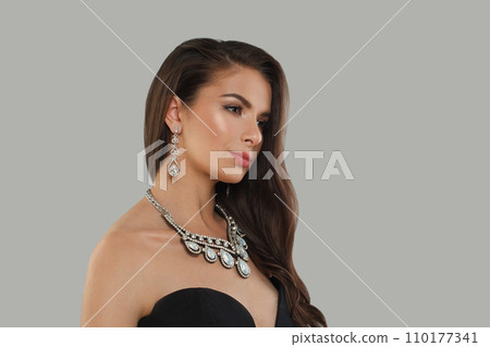 Nice glamorous woman jewelry model with diamonds posing on gray background 110177341