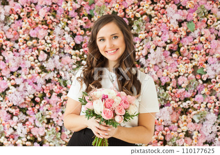 Spring portrait of happy brunette woman with cute smile holding flower gift and posing  110177625